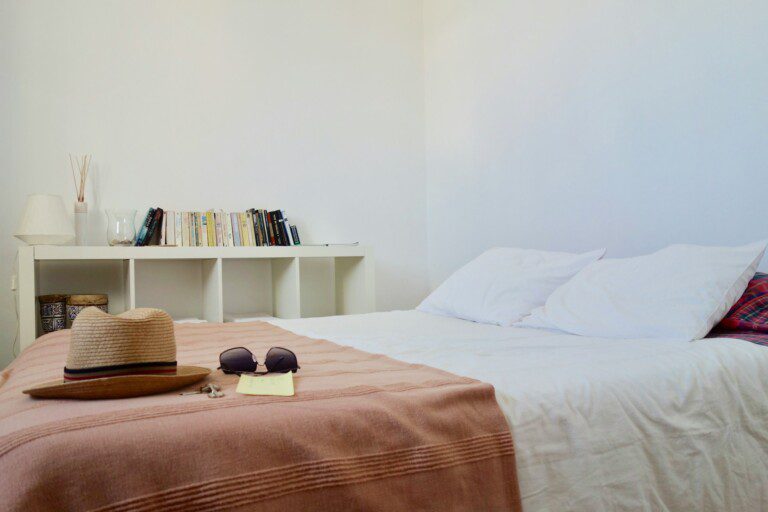 An inviting bed featuring tourist accessories like sunglasses and keys, perfect for families or groups staying in 2 bedroom holiday apartments in Copenhagen